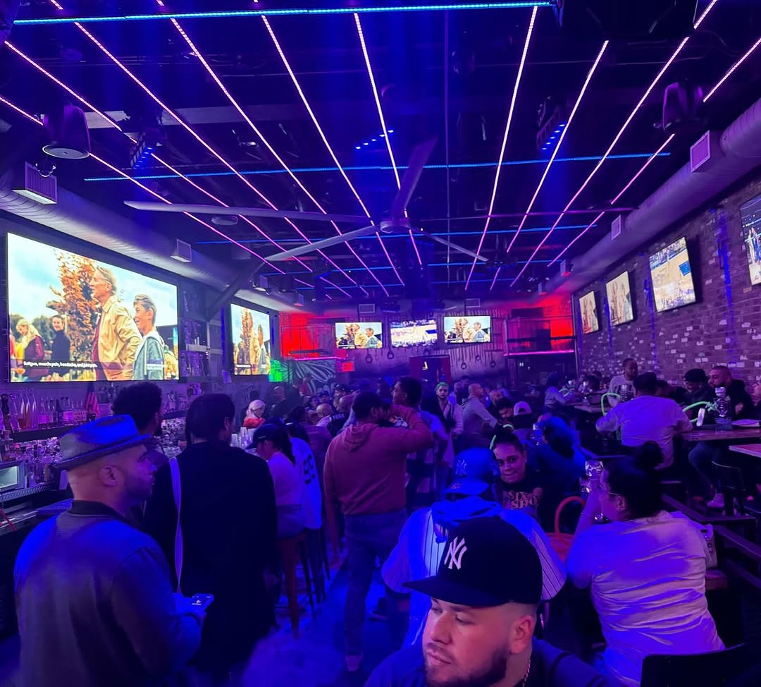 Packed crowd at the bar under neon lights at El Jefe NYC